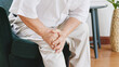 Closeup old Asian senior man feel pain, ache, hurt at knee while standing and sitting at home, osteoarthritis concept