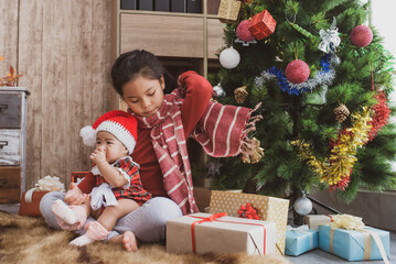 Wall Mural - cheerful cute childrens girls with gifts. kids wearing pajamas having fun near tree in the morning. merry christmas and happy holidays.  loving family with presents in room.