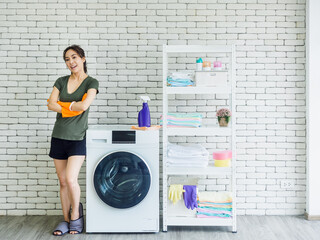 Beautiful Asian woman, housewife wearing orange protective rubber gloves in laundry room.