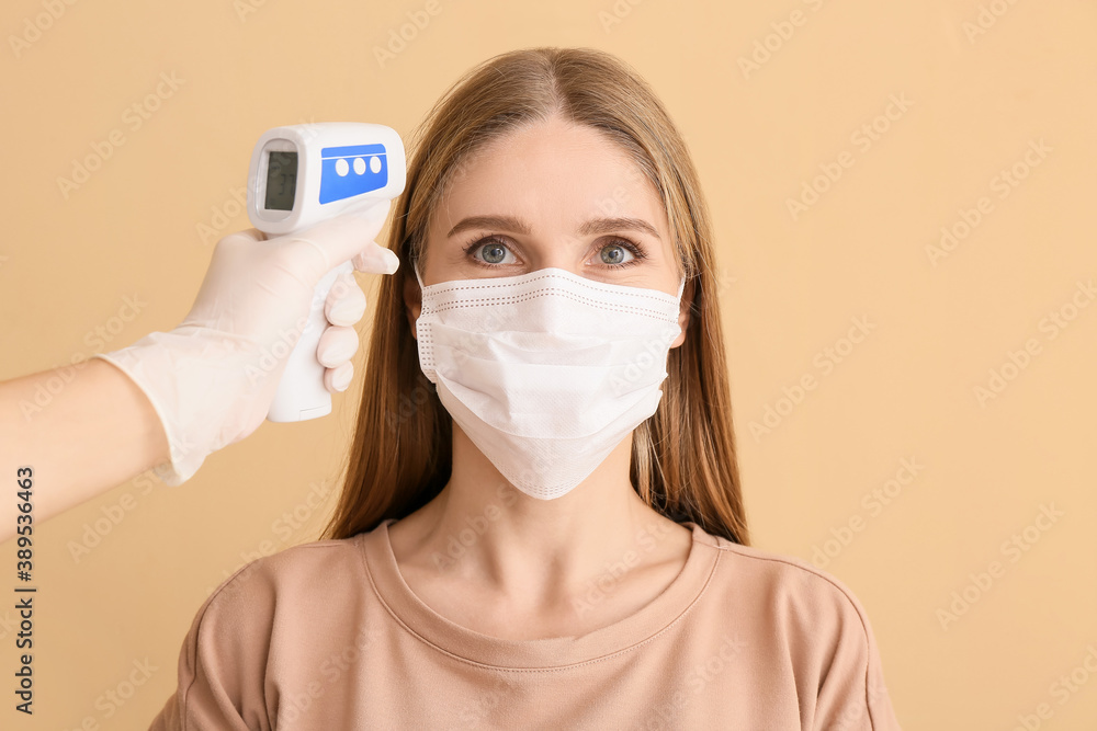 Woman and hand with infrared thermometer on color background. Coronavirus epidemic