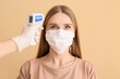 Woman and hand with infrared thermometer on color background. Coronavirus epidemic