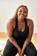 © Roman - plump, plus size african american young woman in sportswear sit looking at camera, in studio over white background.concept of sport, body positive, equality