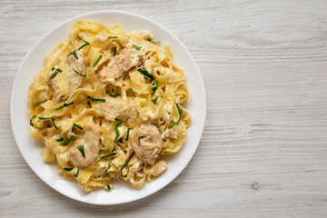 Homemade Chicken Fettuccine Alfredo on a white plate on a white wooden background, top view. Copy space.