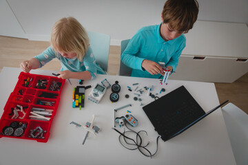 Wall Mural - little girl and boy building robots from colorful plastic blocks
