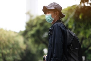 Wall Mural - Asian travelers man in the forest with medical face mask to protection the Covid-19  new normal lifestyle