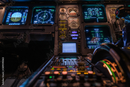 modern airplane cockpit with illuminated instruments - detail view - during night time flight - blurred foreground