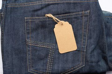 blank brown rectangular tag tied in the back pocket of blue folded jeans