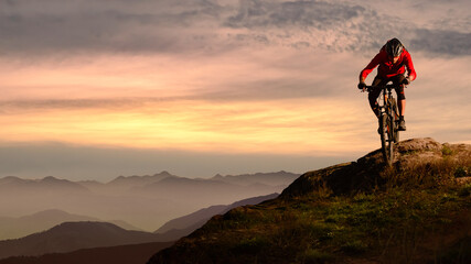 Wall Mural - Cyclist in Red Riding Bike on the Autumn Rocky Trail at Sunset. Extreme Sport and Enduro Biking Concept.