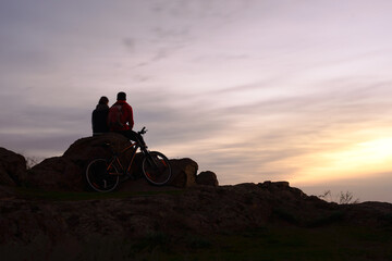 Wall Mural - Young Couple Sitting on the Rock in the Mountains at Night