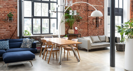 Wall Mural - Interior of living room in industrial style in loft apartment. Brick wall, big wall, wooden table and navy sofa in stylish room at home. Banner.