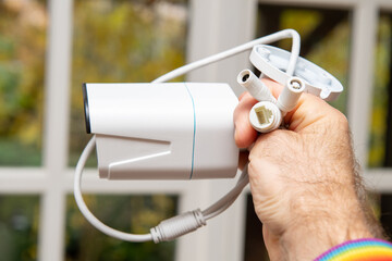 POV male hand holding against home window background new CCTV surveillance camera with AI with Person Vehicle Detection