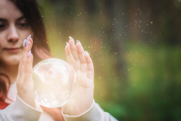 A magical fairy with a mystical crystal ball in the hands of a girl. A fairy tale in real conditions.