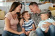 © JustLife - Happy soldier sitting on the floor with his family. Soldier and his wife enjoying at home with children