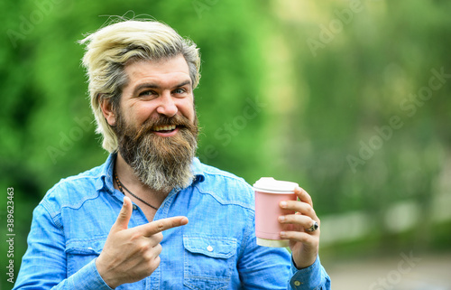 Pleasant morning. Handsome calm bearded man outdoors with a cup of coffee. Man drinking hot coffee. tourist relaxing in park drink tea. Coffee on the go. man with a cup of coffee outdoors