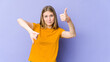 © Asier - Young blonde woman isolated on purple background showing thumbs up and thumbs down, difficult choose concept