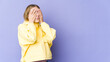 © Asier - Young blonde woman isolated on purple background afraid covering eyes with hands.