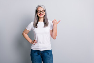 Photo of senior lady direct thumb look empty space wear glasses jeans white t-shirt isolated grey color background