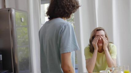 Caucasian gay male couple having argument while having breakfast in morning at home