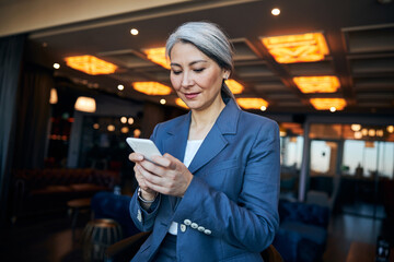 Wall Mural - Charming businesswoman using modern smartphone in cafe