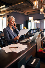 Wall Mural - Cheerful businesswoman having phone conversation at work