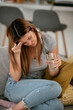 © JustLife - Young woman sick in bed holding glass of water.