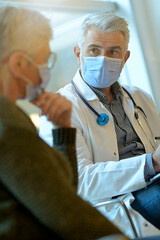 Doctor with face mask listening to patient in office, 19-ncov pandemic