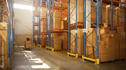 Worker Moves Cardboard Boxes using Manual Pallet Truck, Walking between Rows of Shelves with Goods in Retail Warehouse. People Work in Product Distribution Logistics Center. Side View