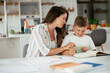 © JustLife - Mother helping her son with homework at home. Little boy learning at home.