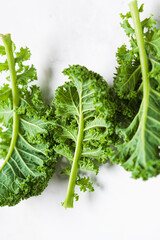 Wall Mural - Fresh green kale leaves on white marble background.