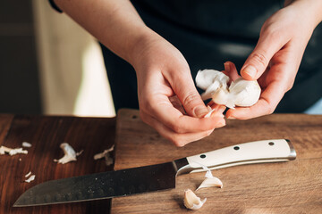 Canvas Print - Female chef peeling garlic on a wooden board
