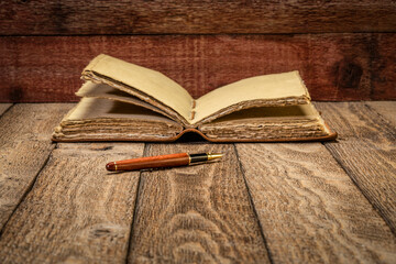 Wall Mural - antique leather-bound journal with decked edge handmade paper pages and a stylish pen on a rustic wooden table, journaling concept