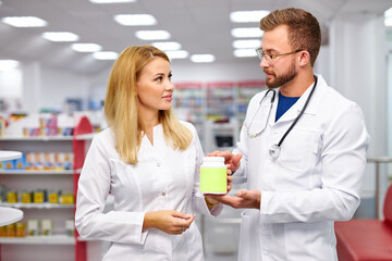 Wall Mural - two young professional druggists colleagues fulfilling a prescription holding medication in hand, checking the script