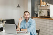 © ViDi Studio - Excited young man sit alone at table in coffee shop cafe restaurant indoor working studying on laptop pc computer holding index finger up with great new idea. Freelance mobile office business concept.
