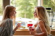© alfa27 - side view on happy blonde women talking and drinking champagne in cafe, at meeting after work. lunch time. relaxed females share news, smiling friends, lifestyle concept