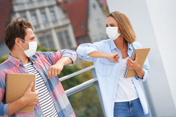 Couple of students wearing masks while saying hi in the campus