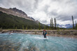 © Cavan Images - Backpacker crosses fast flowing river en route to Castleguard Meadows