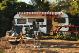 Fototapeta  - Deck chairs and travel accessories near modern trailer. Camping season