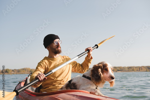 Cuadros en Lienzo Kayaking with dogs: man rowing a boat on the lake with his spaniel
