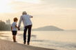 © Garun Studios - father is holding hands their child and walking on the beach at sunset in holiday..Holiday Family on the beach in summer, Travel, vacation and lifestyle concept
