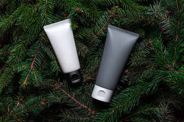 White, grey tubes, bottles of cream or body lotion on green branches background. Two. Pine, fir, spruce. Organic cosmetic. Treatment spa beauty skincare healthcare Brand commercial Product Top view