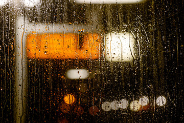 Wall Mural - Close-up and night view of raining water drop on clear transparent glass and defocus background and bokeh of Light rail platform signage.