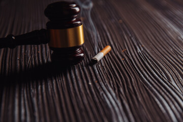 Judge gavel and cigarette on a wooden table. Tobacco law.