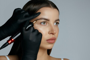 Beauty master applying eyebrow tattooing