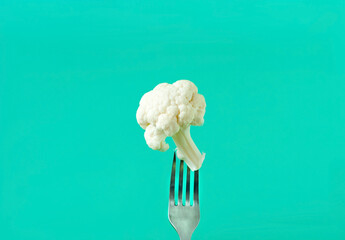 Wall Mural - Cauliflower on an iron fork on a green background . World Vegan Day or Healthy eating concept. Creative copy space.