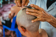 
Close Up Of Asian Man Shaving Hair For Buddhist Ordination Ceremony In Thailand. Preparation For New Thai Monk.