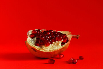 Pomegranate fruit isolated on red background, close-up. Minimalism concept.
