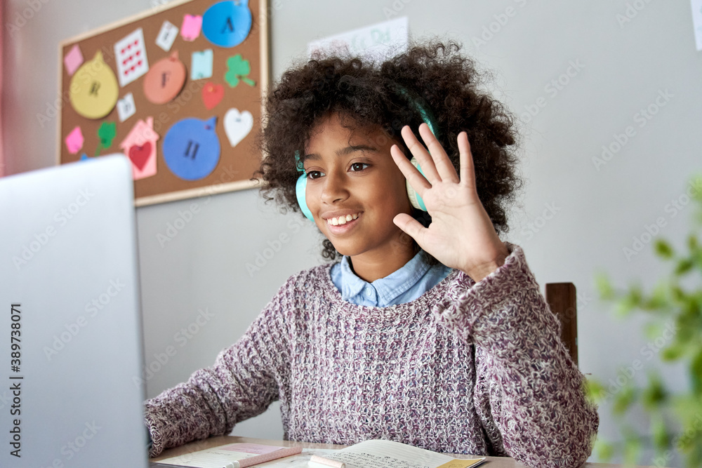 Smart happy african american kid girl wearing headphones waving hand talking with remote web teacher on social distance video conference call elearning class on computer. Children learning at home. - obrazy, fototapety, plakaty 