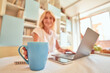 © Friends Stock - Blue cup on kitchen table in front of working woman
