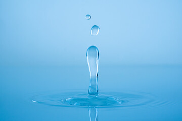 Wall Mural - Water drop splashing into blue water surface