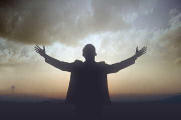 Silhouette of businessman raised hands and praying to god